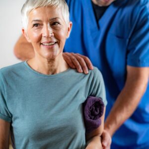 Woman smiles while chiropractor feels her shoulder and back