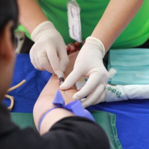 Phlebotomist inserts IV into person's arm