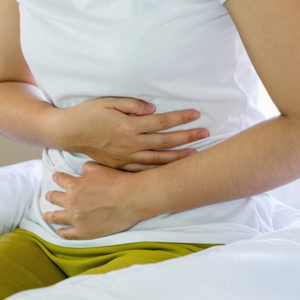 A person holding their stomach, indicating discomfort or an upset digestive system.