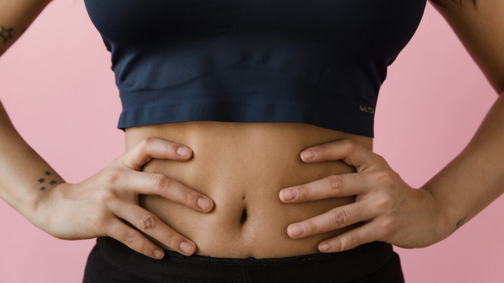 Close-up of a person's midsection with hands on hips, highlighting the abdomen and core.
