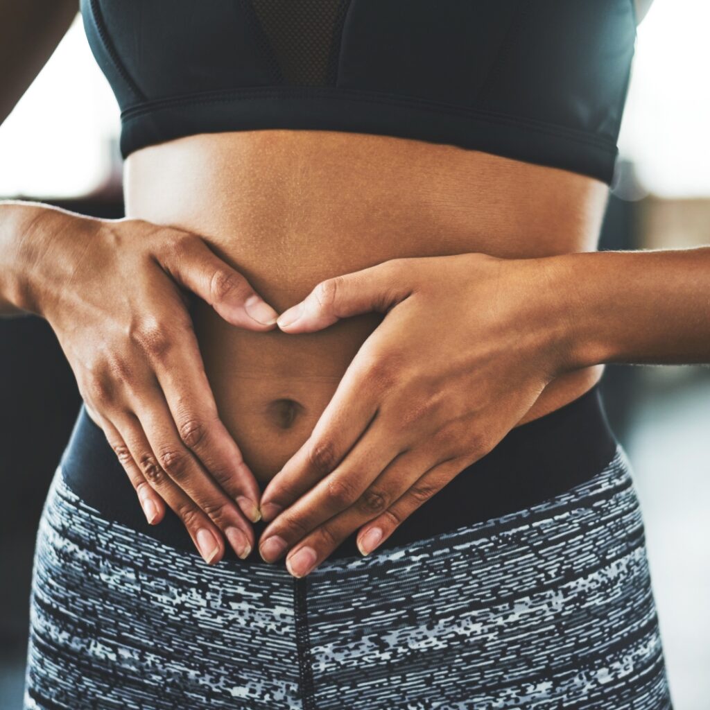 A person making a heart shape with their hands over their stomach, representing gut health and care.