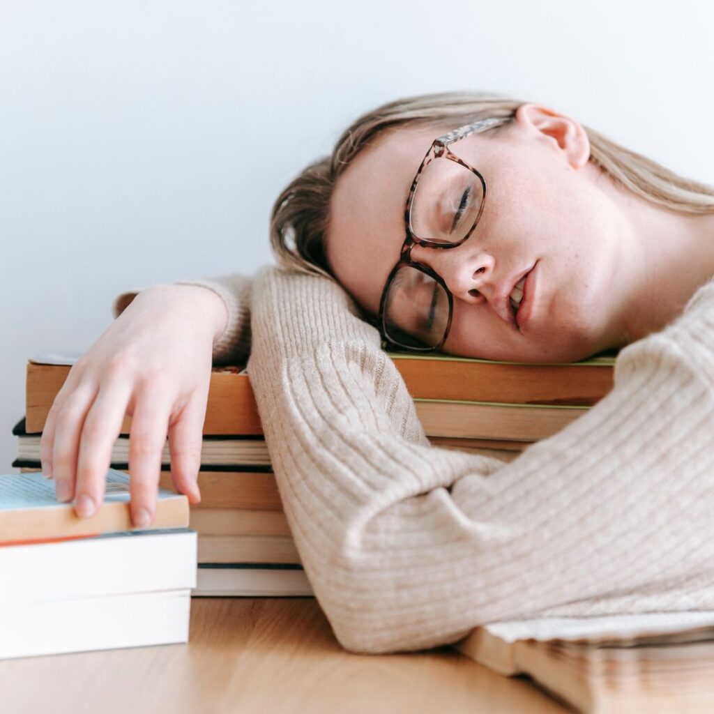 a woman sleeping on a pile of books