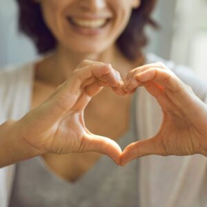 a woman making a heart shape with her hands