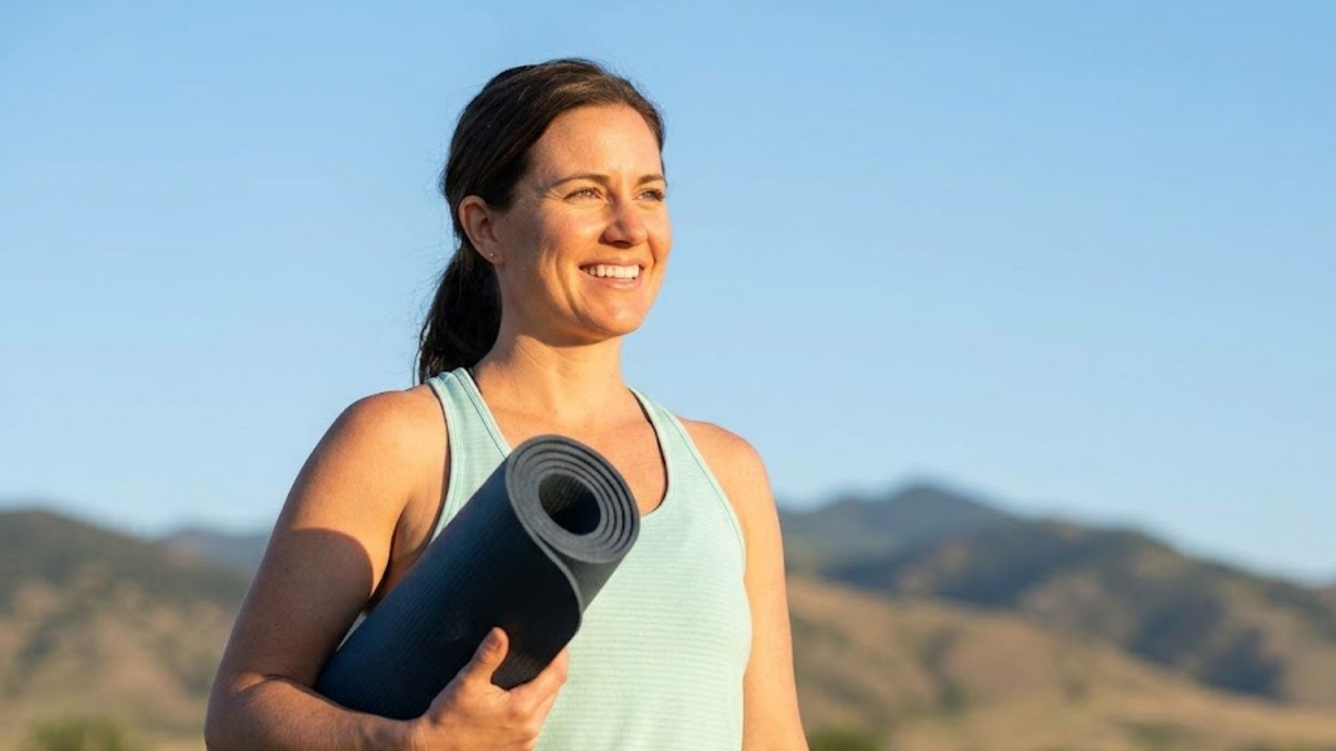 A woman holding a yoga mat.