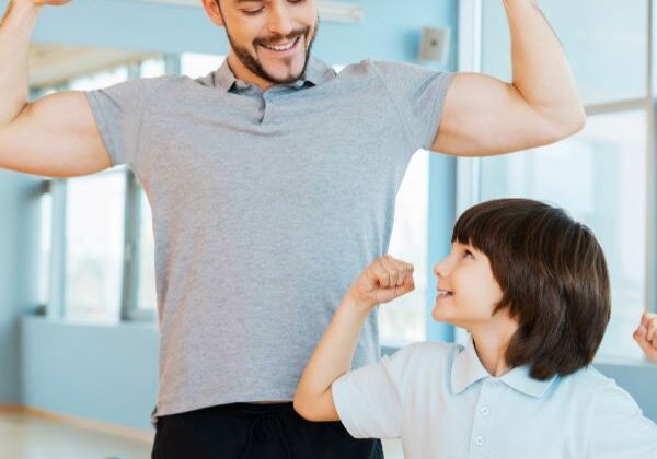 father and son holding up strong arms
